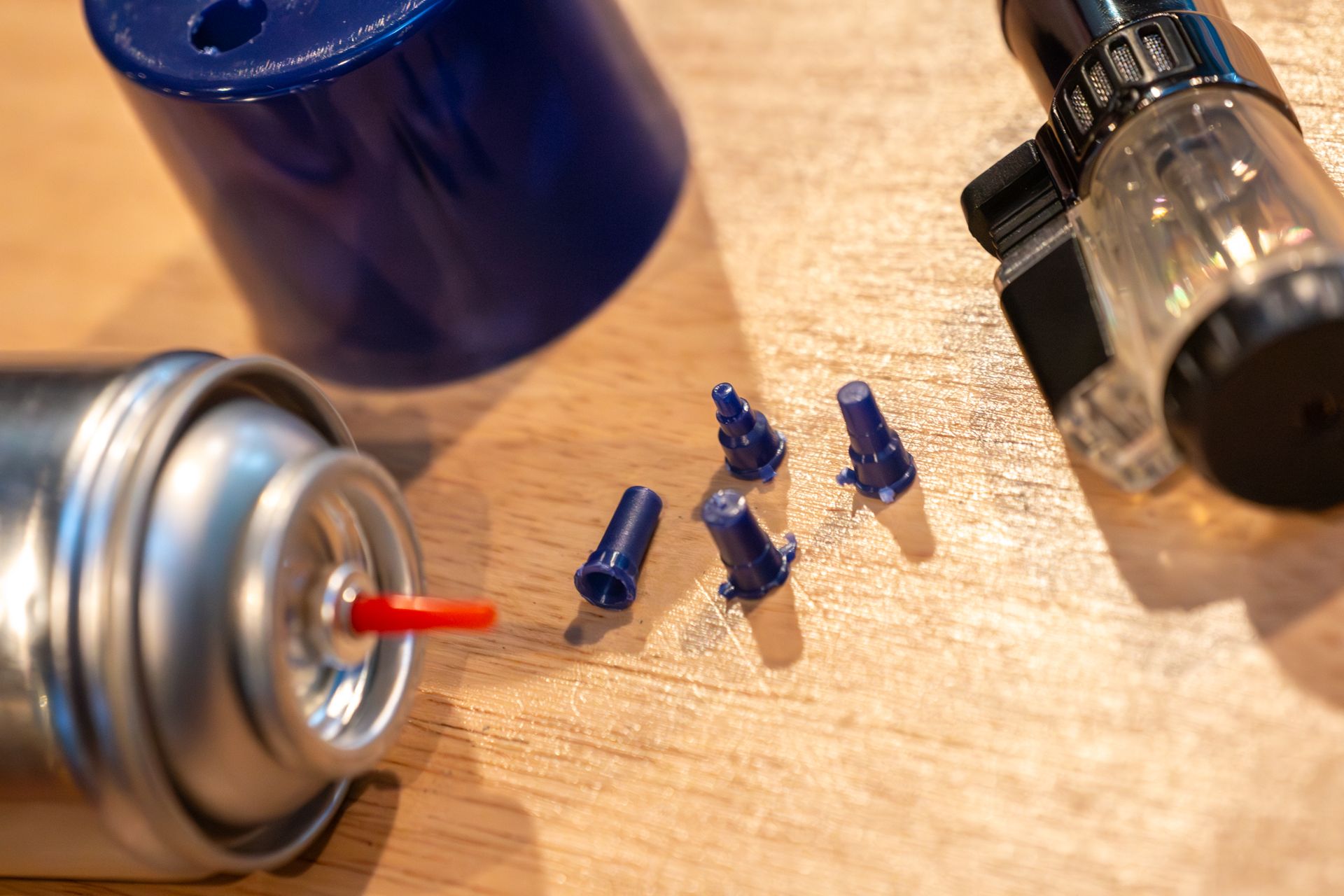 Butane can with refill straw and nozzle tips next to a torch cigar lighter — supplies needed to purge without tools