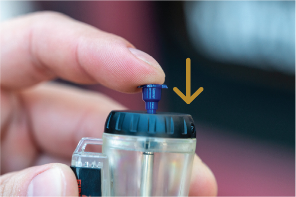 Step 3: Press the refill valve to purge — release air/butane from the valve at the base of the blue tip